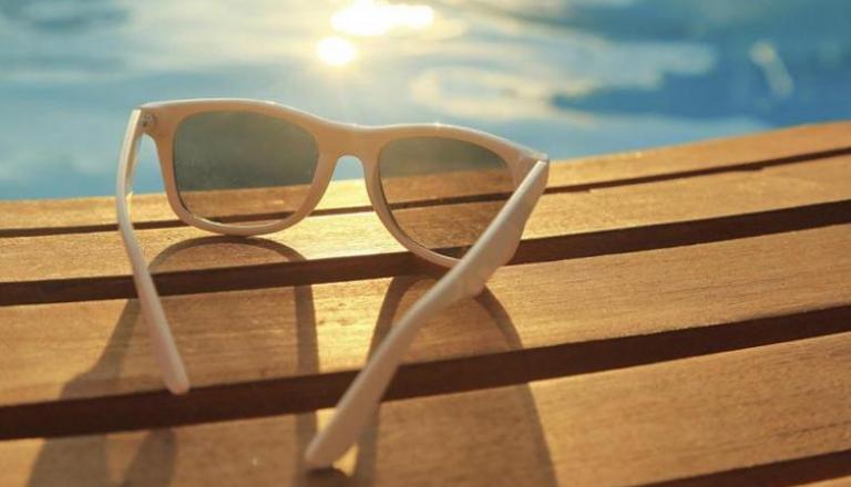 Lentes de sol en una silla de playa junto a una piscina.