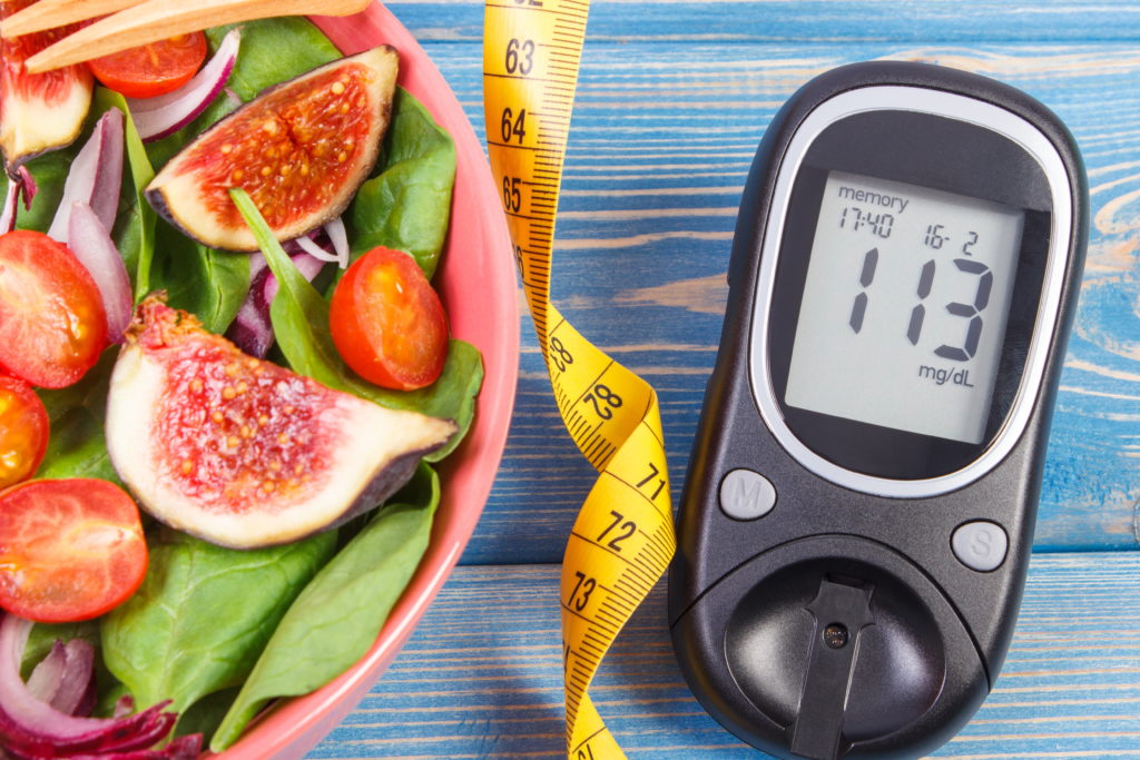 Ensalada de frutas y verduras, y glucómetro con cinta métrica.