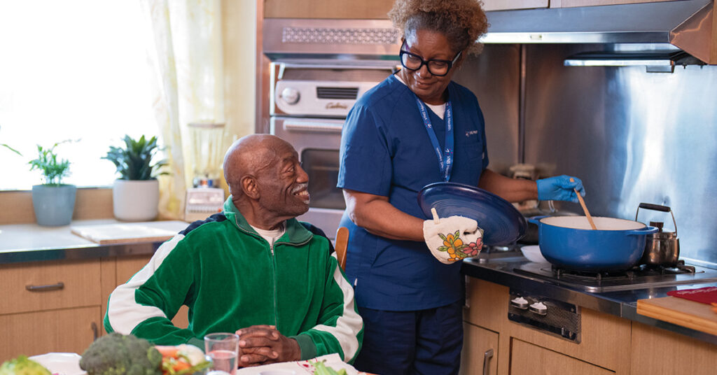 Home Health Aide assisting with cooking for a patient as they look on.